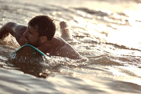 close up of young  male surfer swimming on surfboard, catching the wave. copy space