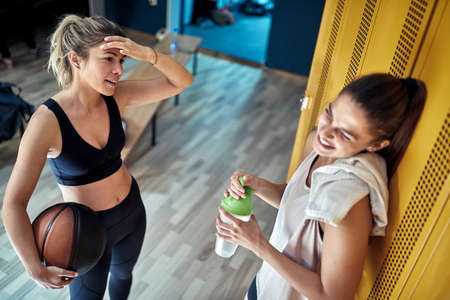 Sporty active girl talking in locker room before basketball training.の写真素材
