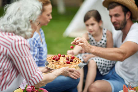 Young  happy family enjoying summer together at backyard and eat pie.の写真素材