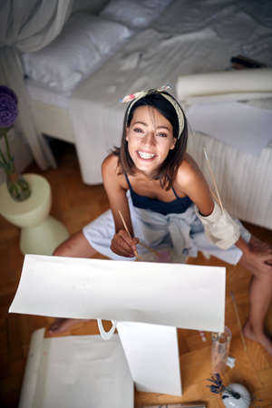 Young sexy girl painter posing while painting in her bedroomの写真素材