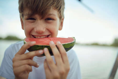 young little minor caucasian boy, eating slice of watermelon