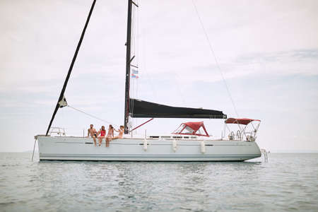 Friends chilling on deck of a yacht on open sea on a sunny day