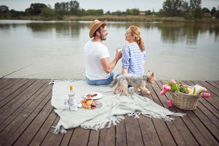Happy spouse enjoying a picnic on the dock of the lakeの写真素材