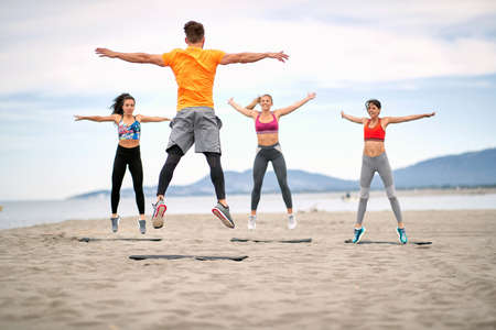 Group of fitness people jumping  and fitness workout on the beach.の写真素材