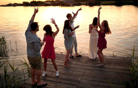 Party at the dock on river at evening. Happy people having fun together.