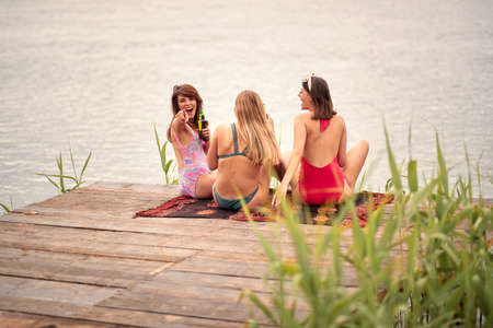 three female friends having fun by the lakeの写真素材