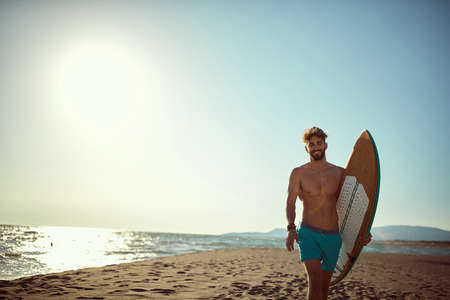 Sexy surfer posing on the beach with surfboard