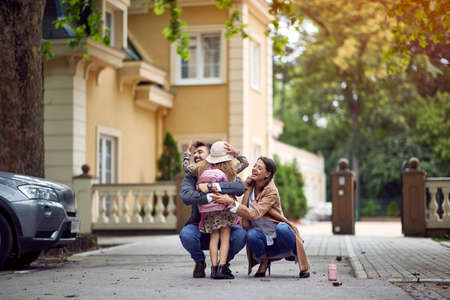 Mom and dad embracing daughter after schoolの写真素材