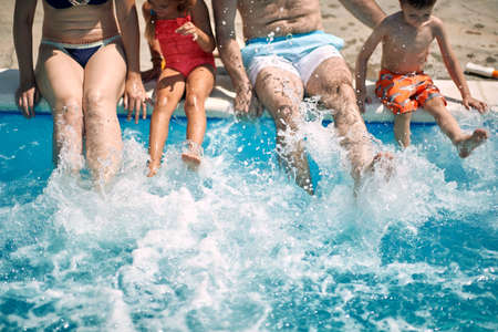 Happy family splashed water with foot at pool before swimming.