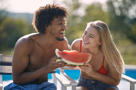 Smiling  couple  enjoy on summer holiday near swimming pool and  eating watermelon.の写真素材