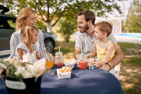 Father and mother with smiling children  sitting at table outdoor and  enjoying together.の写真素材