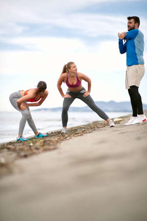 Group of friends stretching together on the beachの写真素材