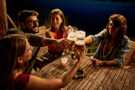 Group of friends having a toast in the bar on the lake with a beautiful night