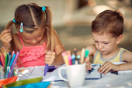 Happy cute children sitting at garden  and they draw together.の写真素材