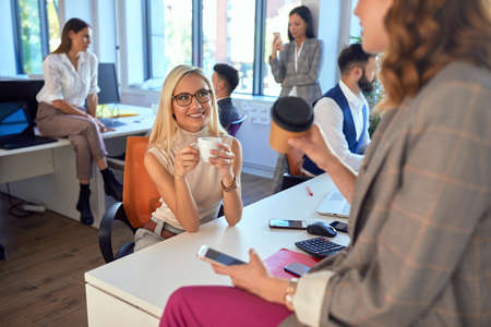 Young women coworkers talking to each other in the office on a brake
