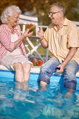 Romantic happy senior man and woman  enjoy on summer holiday near swimming pool and  eating watermelon.の写真素材