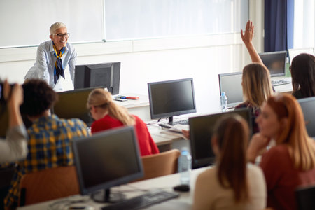 Cheerful teacher in classroom talking with pupilsの写真素材