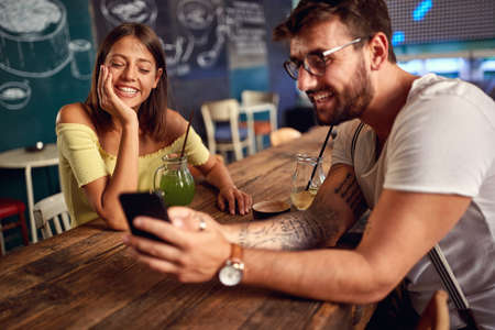 Young couple enjoying the drink and cell phone content in a cafeの写真素材