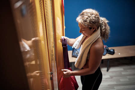 Young sporty girl in a locker room taking the equipment for a trainingの写真素材