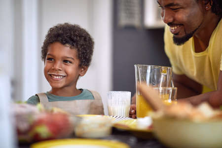 cute little african boy smiling, having breakfast with his dad, making funny faceの写真素材