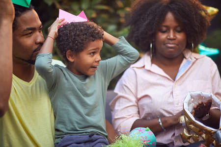 afro-american family playing together with paper hats at birthday party. togetherness, bond conceptの写真素材