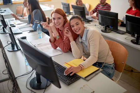 Female students smiling and posing at an informatics lecture in the university computer classroomの写真素材