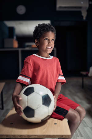A little soccer player in a locker room posing ready for a training