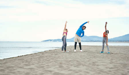 Friends doing fitness with the music on the beach on a beautiful weather