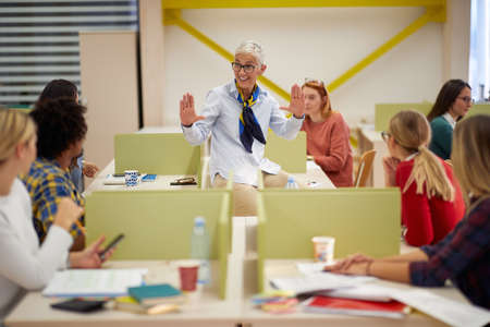 Female professor giving an explanation of the lesson to students at a lecture in a classroomの写真素材
