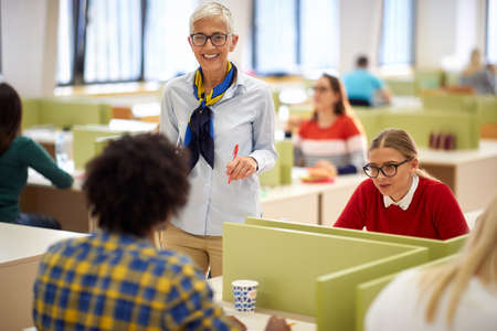 Female professor talking to a student in a classroomの写真素材