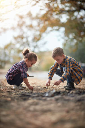 Preschool brother and sister playing in the park together; Spring or autumn hiking in nature; camping, travel, tourism,lifestyle,  hike and people concept. Quality active family time together.の写真素材