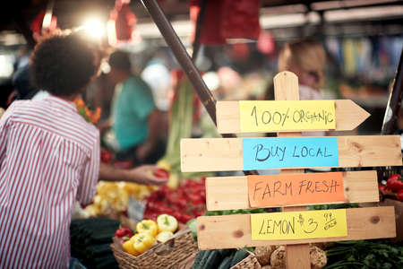 Sign for fresh and organic vegetables and fruits at the green market or farmers market stall.  Young buyers choose and buy products for healthy food in grocery. All for diet healthy eating, lifestyle.の写真素材