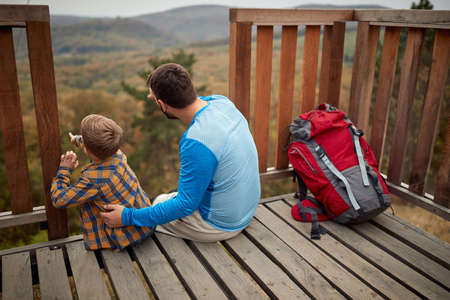Father and son enjoying the view together on a peakの写真素材