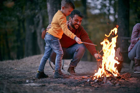 Father and son starting a fire together on a camping; Quality family time conceptの写真素材