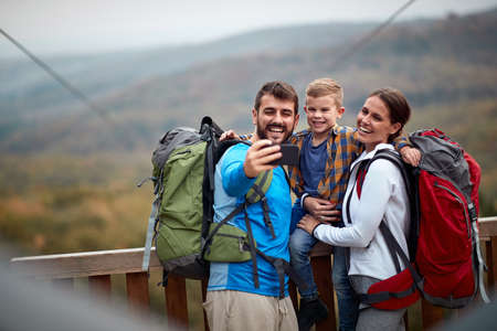 A happy family taking selfie on the top of a watchtower in the forest on a beautiful autumn dayの写真素材
