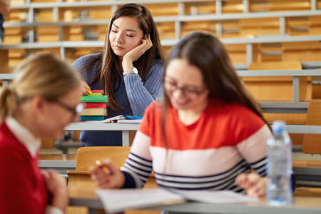 Female student taking a nap at the desk at the lecture in the university classroomの写真素材