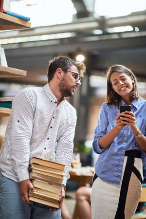 Young couple picked too much books at a cafes library