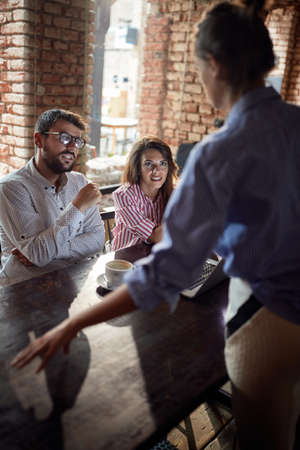 The waitress silences the young couple who loudly celebrating the result of the match watching on the laptop at a cafeの写真素材