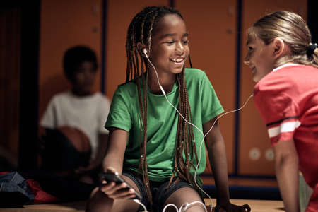 Kids listening to the music while waiting for a training at the locker room. Children team sport
