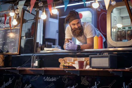 young male employee in fast food service waiting for customers leaned on deskの写真素材