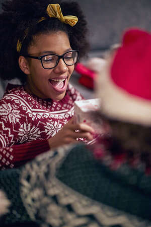 Excited afro american teenage girl reciving xmas gift; Happy family moments conceptの写真素材