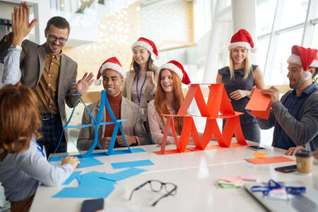 people at office playing, building card towers with santa hats.の写真素材