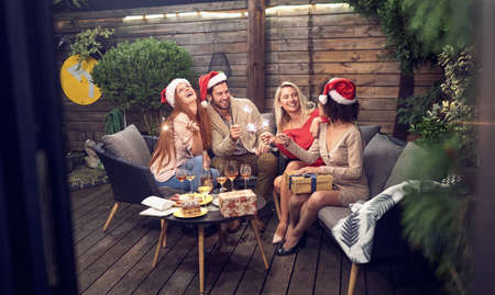 one young beardy caucasian man celebrating new year in the company of three women, sitting outdoor in the backyard, holding sparkling sticksの写真素材