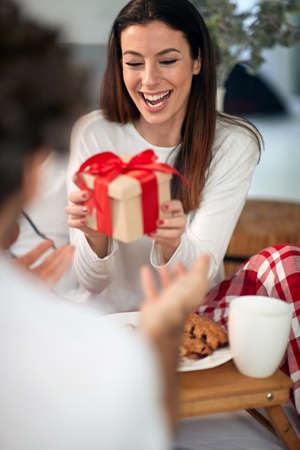 Portrait of a happy woman receiving Chrismas gift in a bedの写真素材