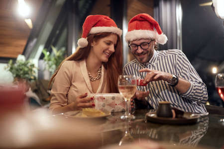 young caucasian couple exchanging presents with santa hats. christmastime,