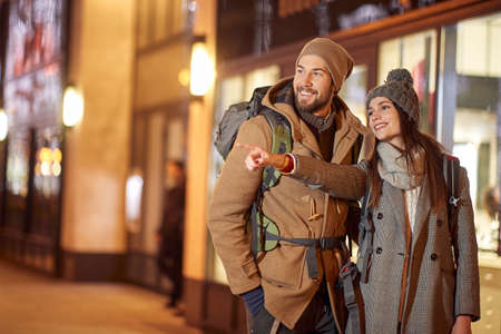 young female tourist showing to another direction with index finger, smiling. new year holdays traveling conceptの写真素材