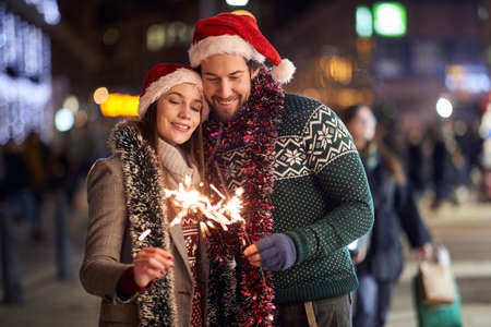 A lovely couple holding sprinklers while walking the city on a Xmas together on a beautiful holiday night. Christmas, relationship, loveの写真素材