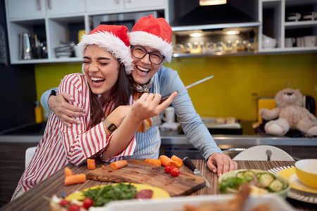 Cheerful mother and daughter posing for a photo while preparing a Xmas meal in a festive atmosphere in the kitchen. Christmas, family, togetherの写真素材