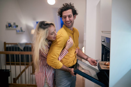 Happy couple baking at home together in the kitchenの写真素材