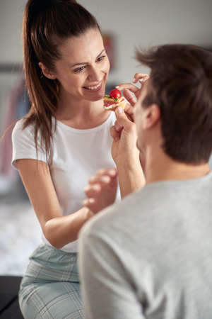 A young couple enjoying playing with the food during a breakfast in a cheerful atmosphere at home....